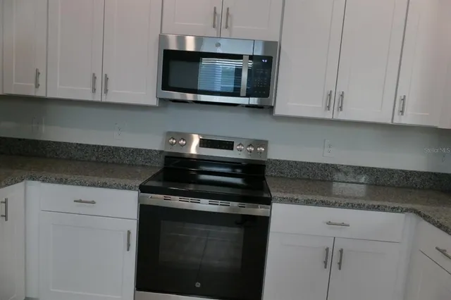 a kitchen with stainless steel appliances granite countertop white cabinets granite counter tops and a hard wood floors