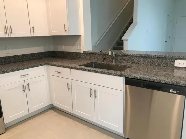 a kitchen with granite countertop white cabinets and a sink
