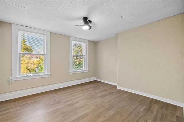 an empty room with wooden floor and windows