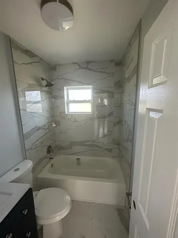 a bathroom with a granite countertop toilet a sink and bathtub