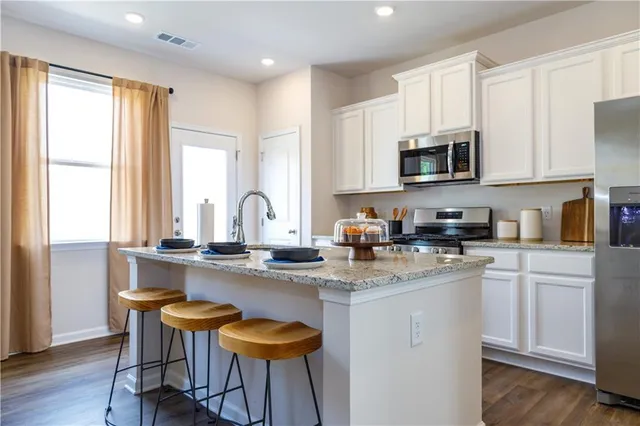 a kitchen with stainless steel appliances granite countertop white cabinets a sink and a stove