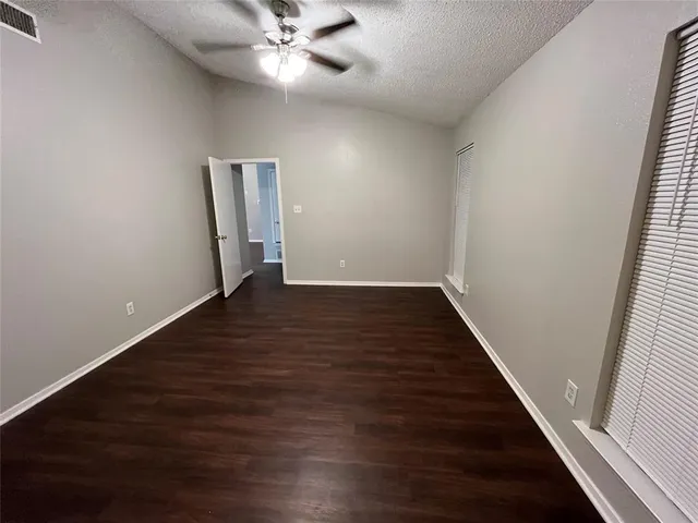 an empty room with wooden floor fan and windows