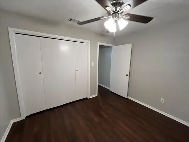 an empty room with wooden floor closet and fan