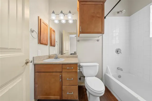 a bathroom with a toilet sink vanity granite and shower