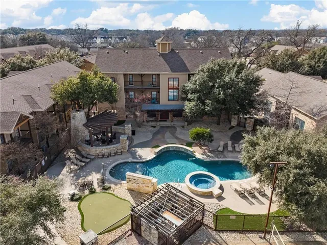 an aerial view of a house with swimming pool and a yard