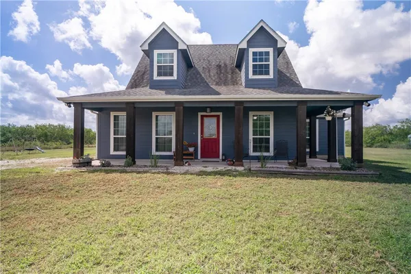 a view of a white house with large windows and a big yard