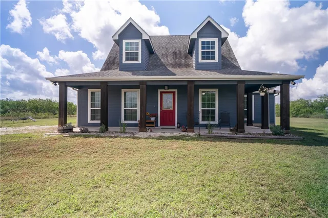 a view of a white house with large windows and a big yard