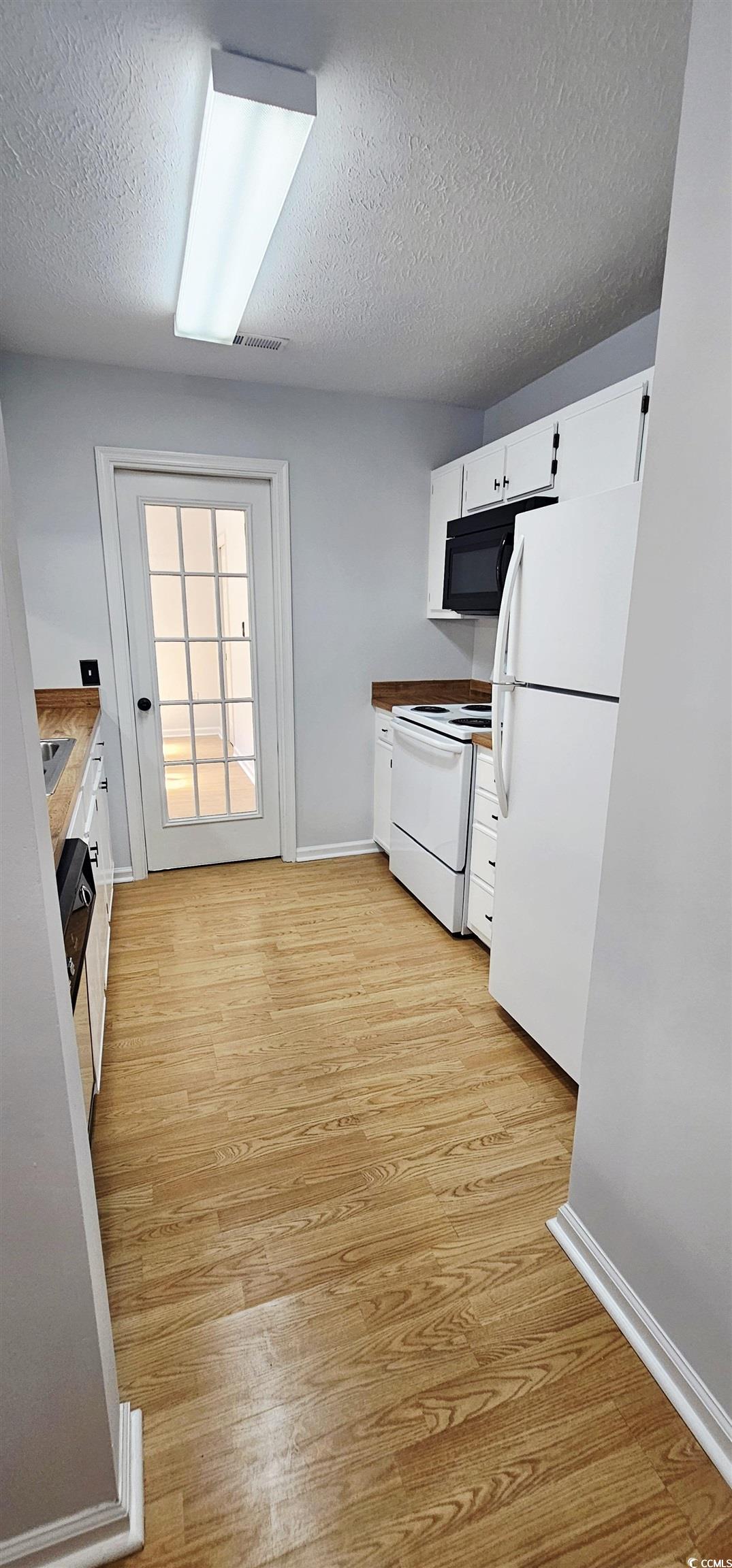 615 13th Avenue South, Unit 137 Surfside Beach, SC 29575 - Photo 23 of 40 Kitchen with white cabinetry, white appliances, light wood-type flooring, and a textured ceiling