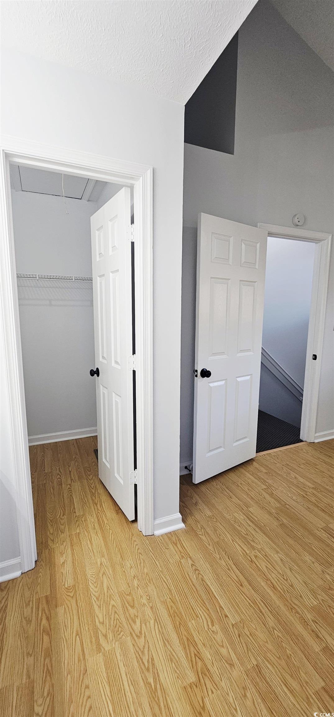 615 13th Avenue South, Unit 137 Surfside Beach, SC 29575 - Photo 32 of 40 Unfurnished bedroom featuring attic access, light wood finished floors, a closet, lofted ceiling, and a textured ceiling