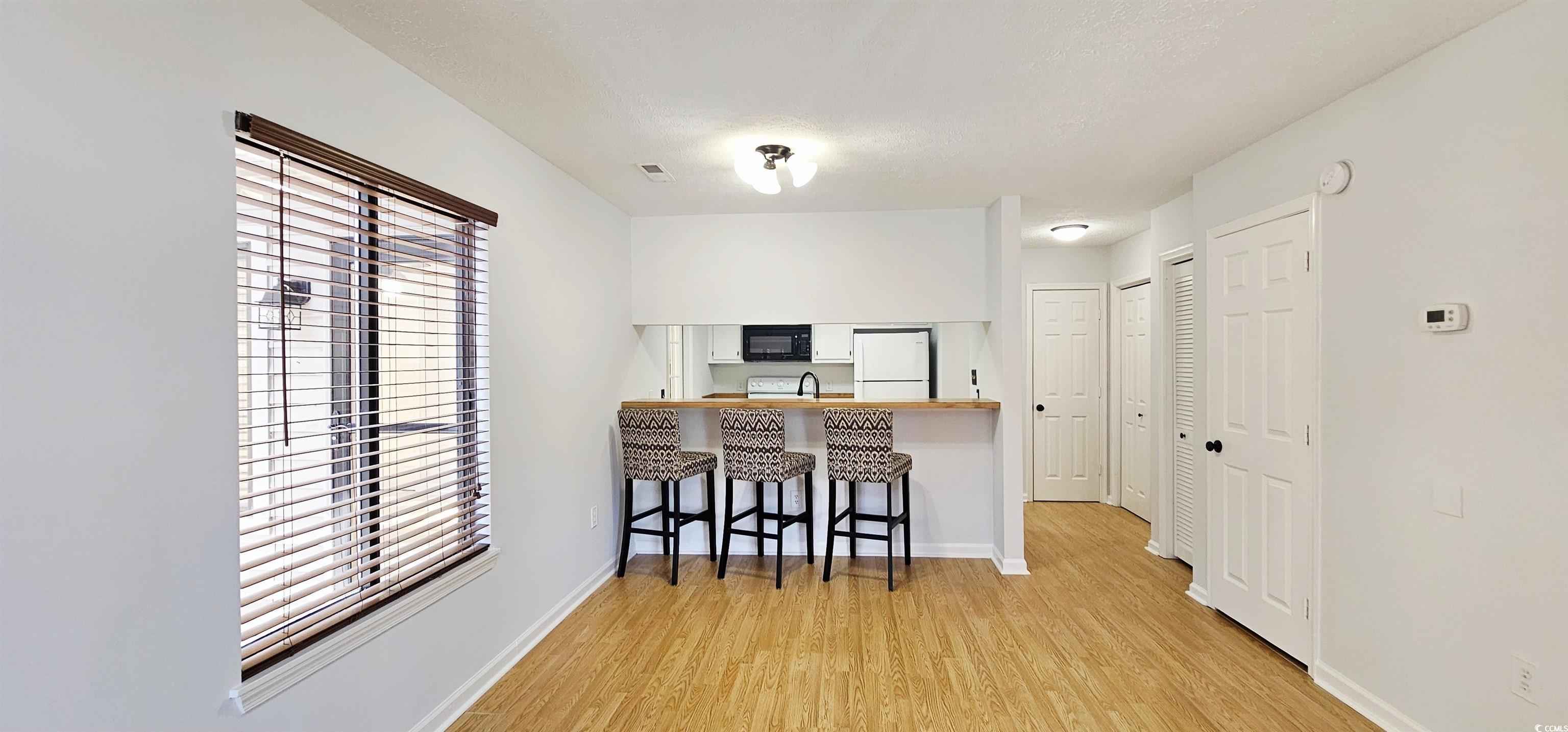 615 13th Avenue South, Unit 137 Surfside Beach, SC 29575 - Photo 4 of 40 Kitchen featuring a kitchen bar, light wood-style flooring, freestanding refrigerator, a peninsula, and black microwave