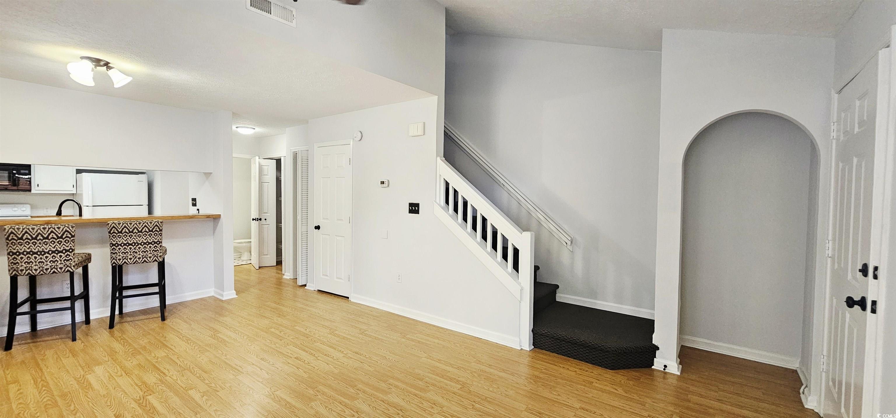 615 13th Avenue South, Unit 137 Surfside Beach, SC 29575 - Photo 10 of 40 Kitchen with a breakfast bar, light wood-type flooring, freestanding refrigerator, arched walkways, and black microwave