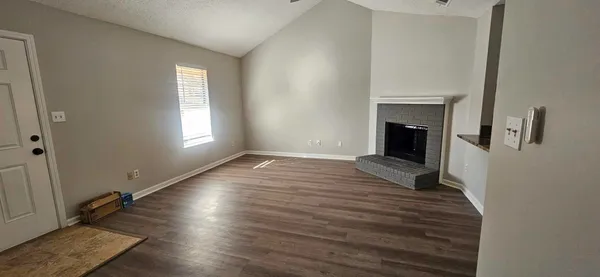 a view of empty room with a fireplace and wooden floor