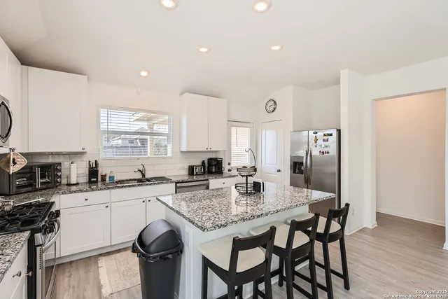 a kitchen with granite countertop a sink stove and refrigerator