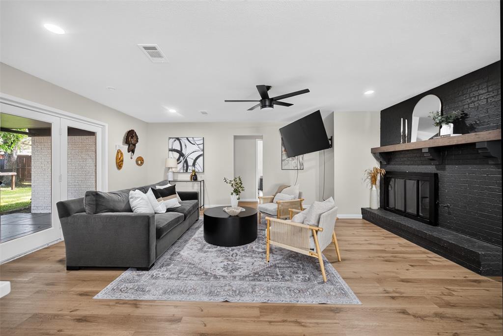 3919 Ridgeoak Way Farmers Branch, TX 75244 - Photo 10 of 28 Living area featuring wood-finish flooring, a black brick fireplace with a wood mantel, and ceiling fan