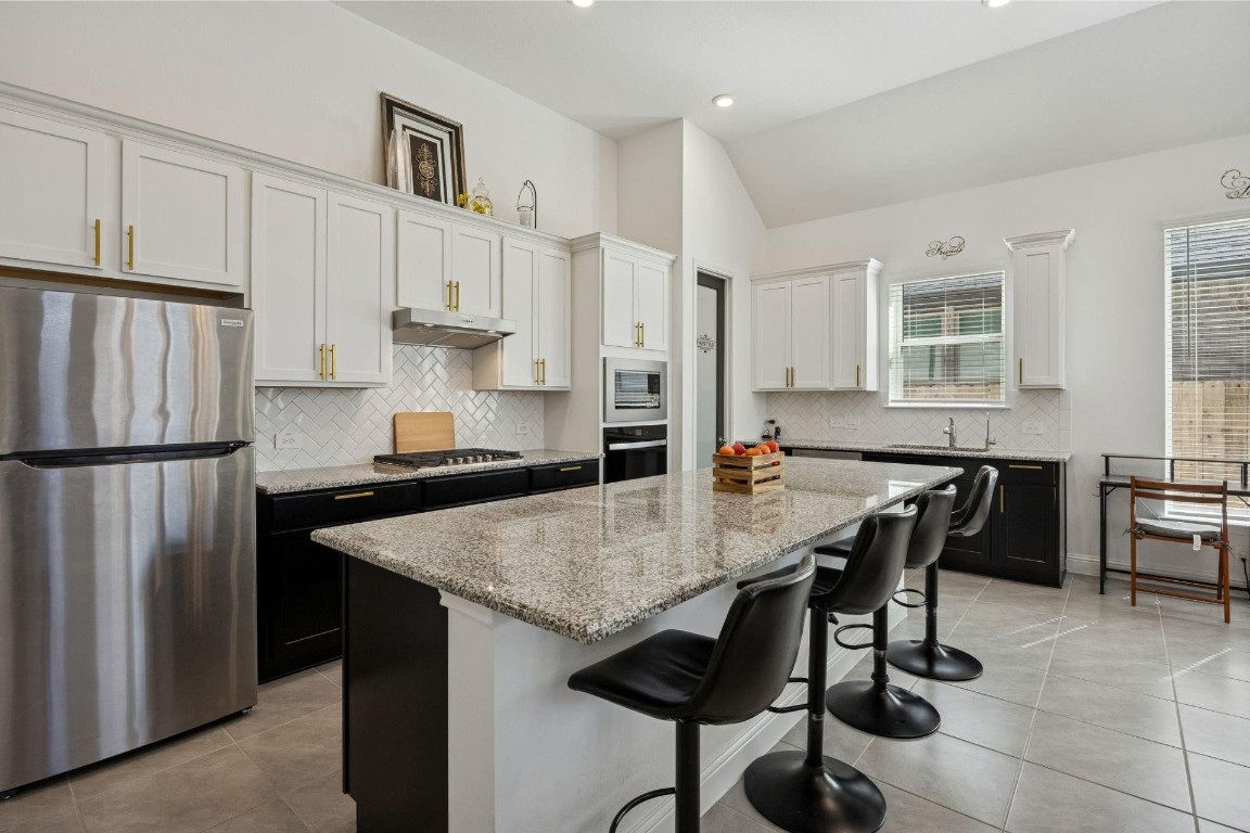 16022 Tangled Vine Lane Conroe, TX 77302 - Photo 5 of 30 a kitchen with stainless steel appliances granite countertop a table chairs and a refrigerator