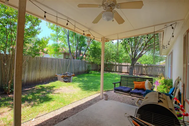 a backyard of a house with table and chairs potted plants and a wooden fence