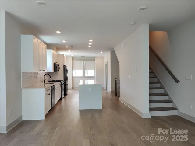 a large kitchen with stainless steel appliances granite countertop a stove a sink a refrigerator and white cabinets