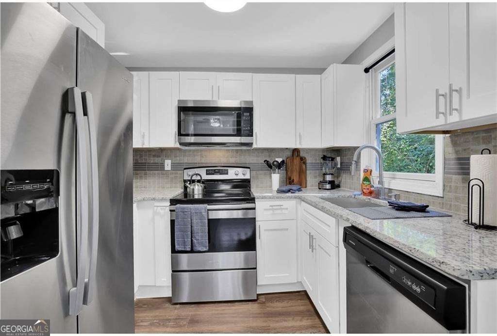 3162 Oakdale Road Hapeville, GA 30354 - Photo 12 of 26 a kitchen with white cabinets and stainless steel appliances