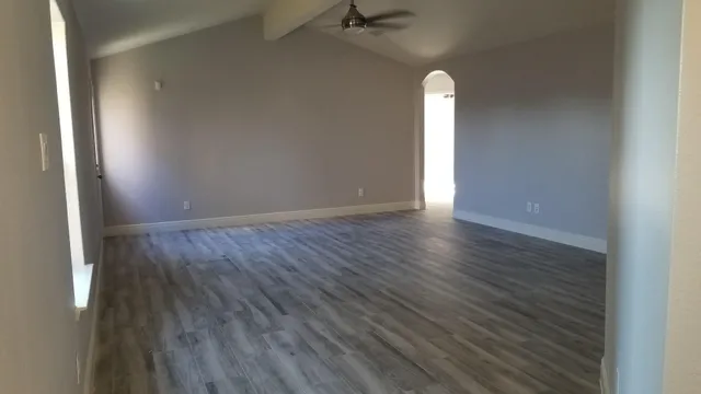 a view of empty room with wooden floor and window
