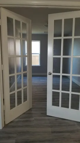 a view of an empty room with wooden floor and windows