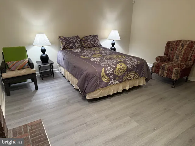 a spacious bedroom with a bed a couch and a dresser with wooden floor
