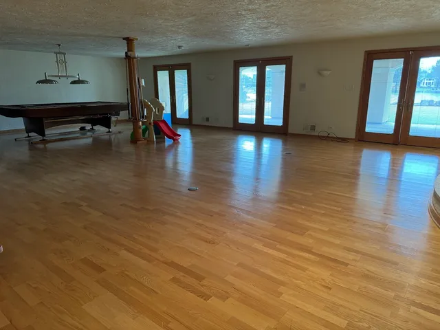 a view of an empty room with wooden floor and windows