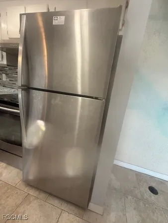 a view of a refrigerator in kitchen and an empty room