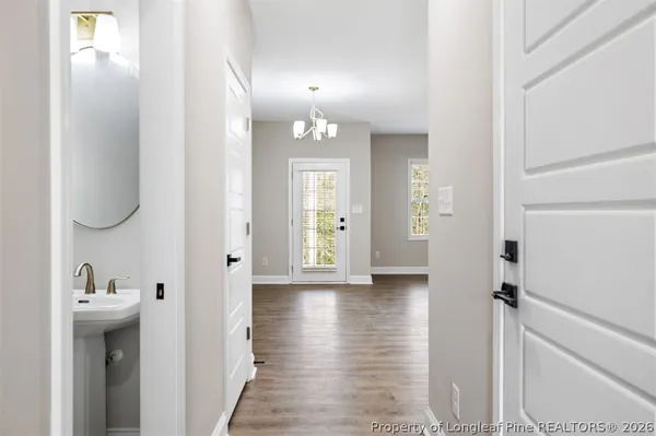 a view of a hallway with wooden floor and a bathroom
