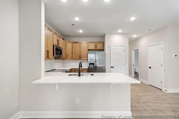 a large kitchen with a large counter top a sink stainless steel appliances and cabinets