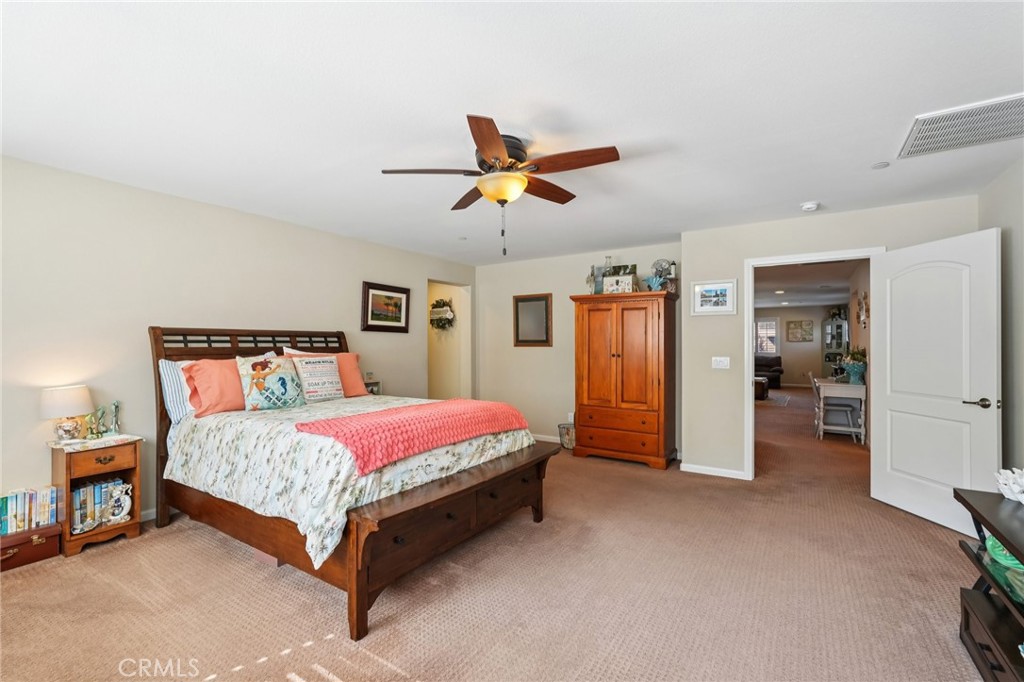 36274 Waxen Road Lake Elsinore, CA 92532 - Photo 16 of 65 a spacious bedroom with a bed and a chandelier