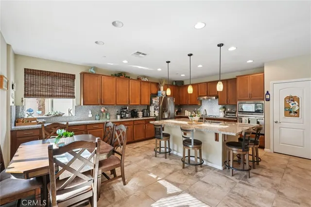 a open kitchen with stainless steel appliances granite countertop a stove top oven dining table chairs and a view of living room