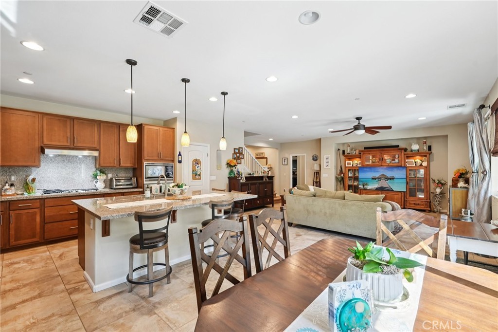 36274 Waxen Road Lake Elsinore, CA 92532 - Photo 7 of 65 a open kitchen with stainless steel appliances granite countertop a stove top oven dining table chairs and a view of living room