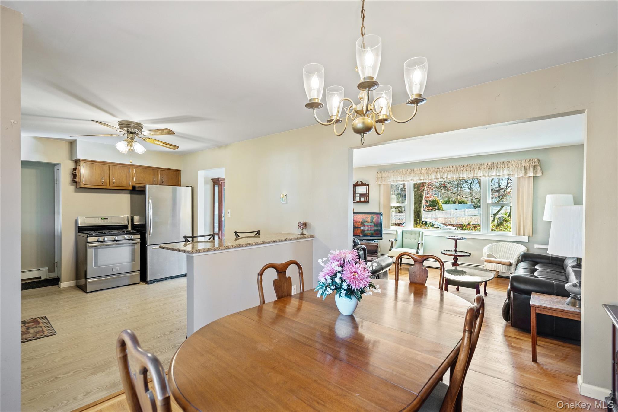 211 Mooney Pond Road Selden, NY 11784 - Photo 11 of 41 a dining room with wooden floor a chandelier a wooden table and chairs