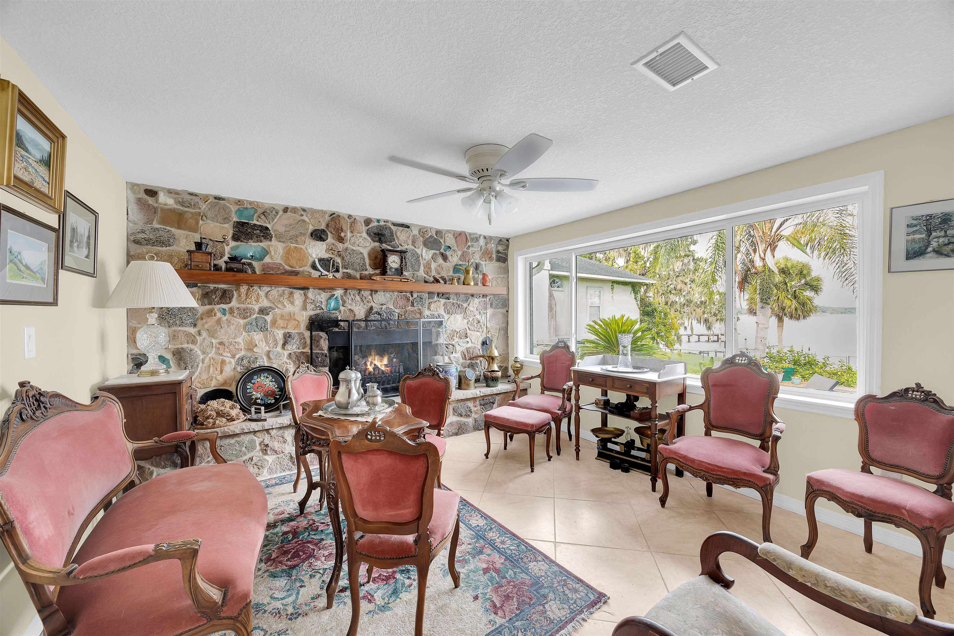 115 Sunset Point Road East Palatka, FL 32131 - Photo 40 of 67 Living area featuring a stone fireplace, a textured ceiling, tile patterned flooring, and a ceiling fan