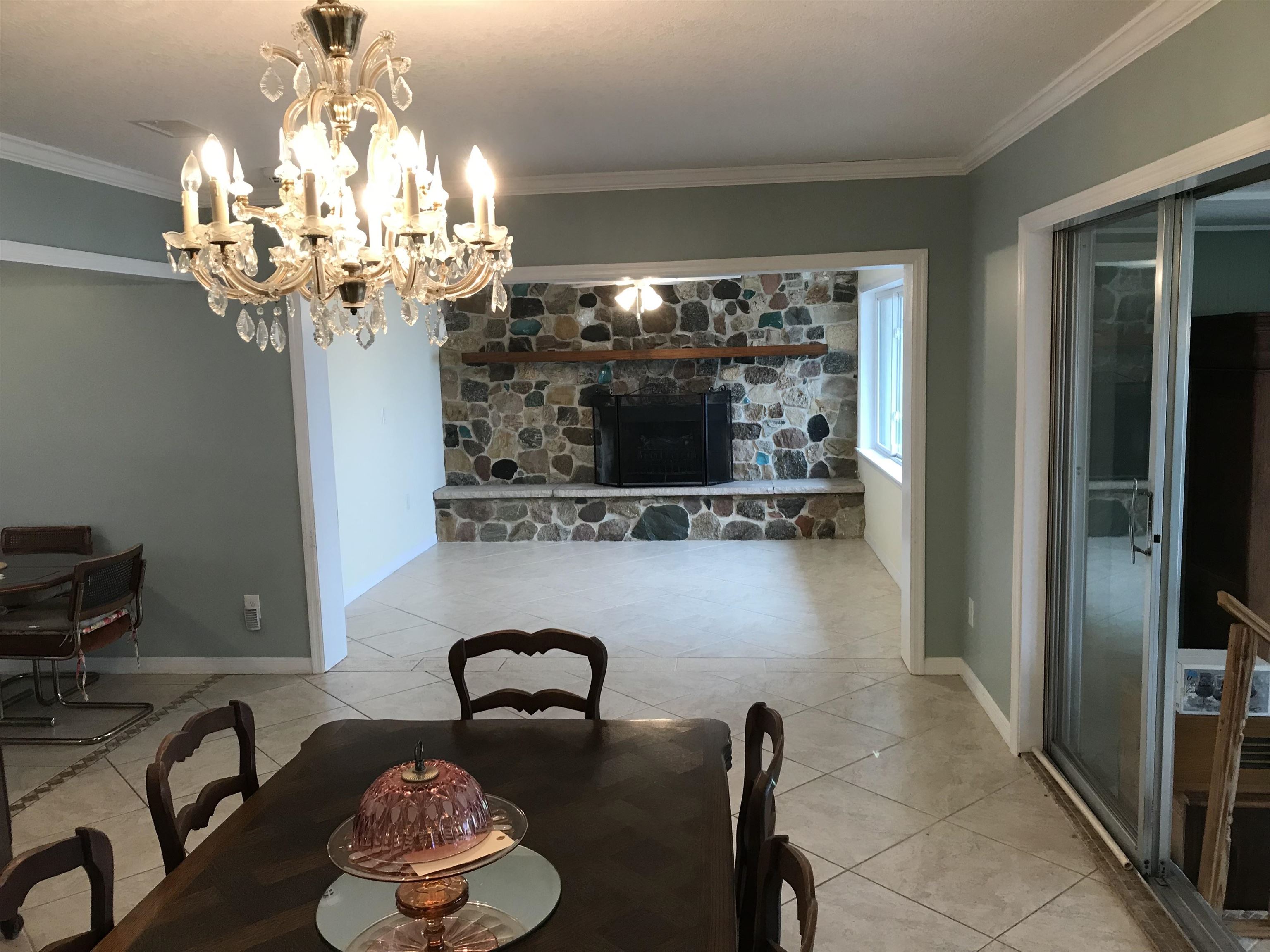 115 Sunset Point Road East Palatka, FL 32131 - Photo 42 of 67 Dining room featuring a stone fireplace, ornamental molding, a chandelier, and light tile patterned floors