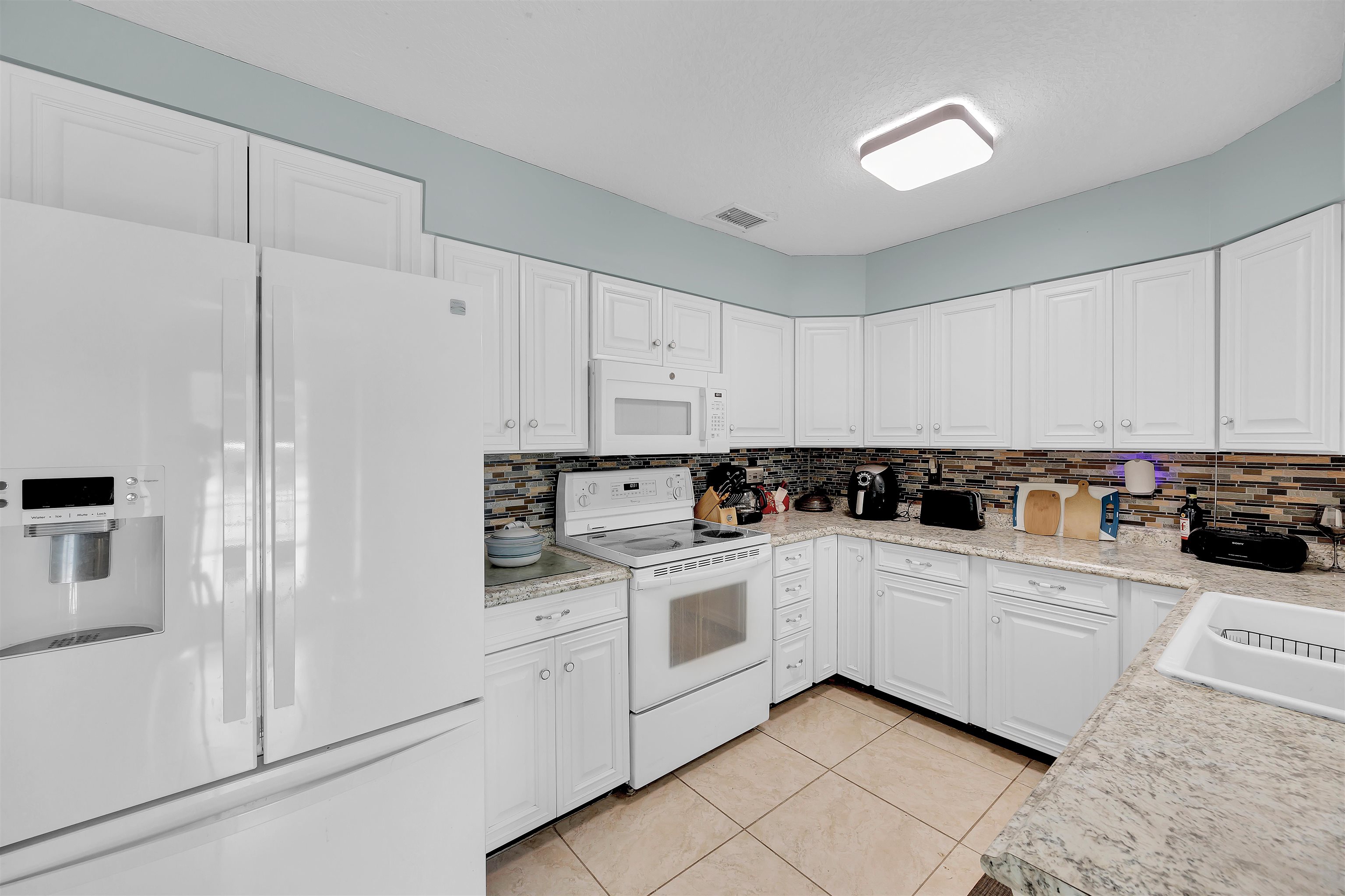 115 Sunset Point Road East Palatka, FL 32131 - Photo 50 of 67 Kitchen featuring white appliances, light countertops, white cabinets, decorative backsplash, and light tile patterned flooring