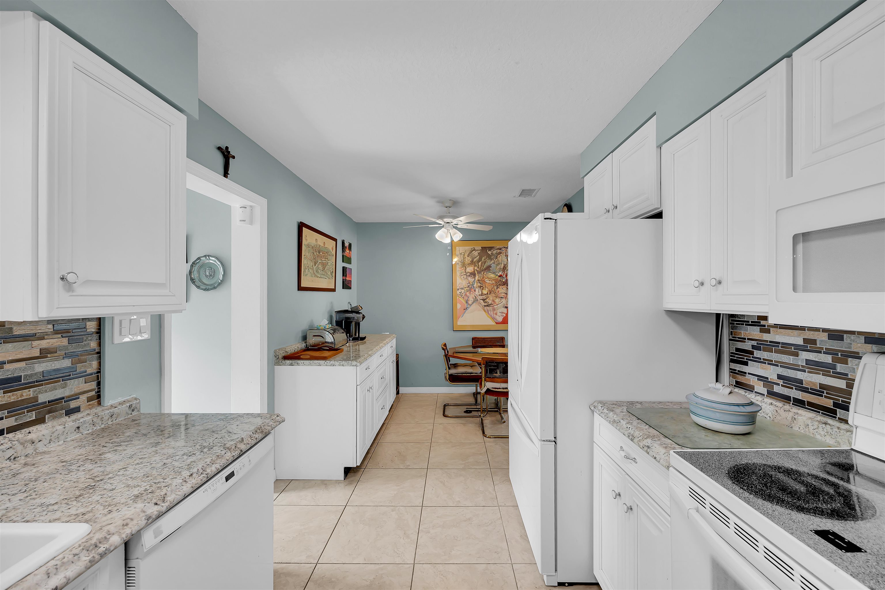 115 Sunset Point Road East Palatka, FL 32131 - Photo 52 of 67 Kitchen featuring backsplash, white appliances, white cabinets, and light tile patterned floors