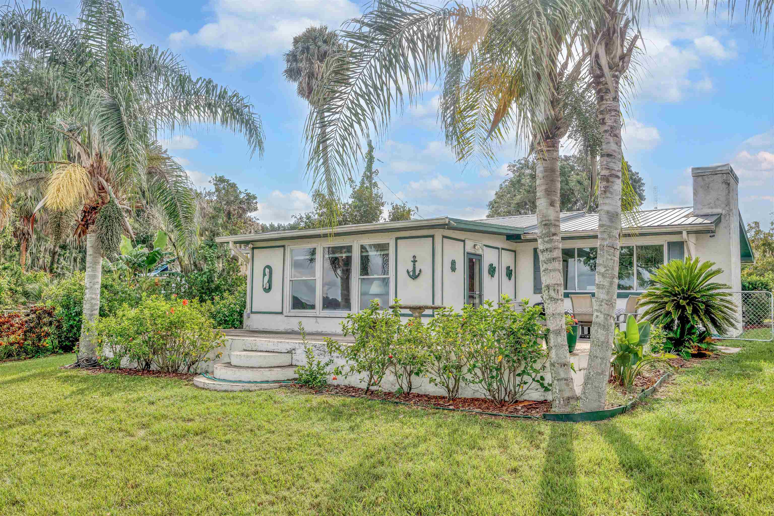 115 Sunset Point Road East Palatka, FL 32131 - Photo 55 of 67 View of front of home featuring stucco siding, a front lawn, a metal roof, and a chimney