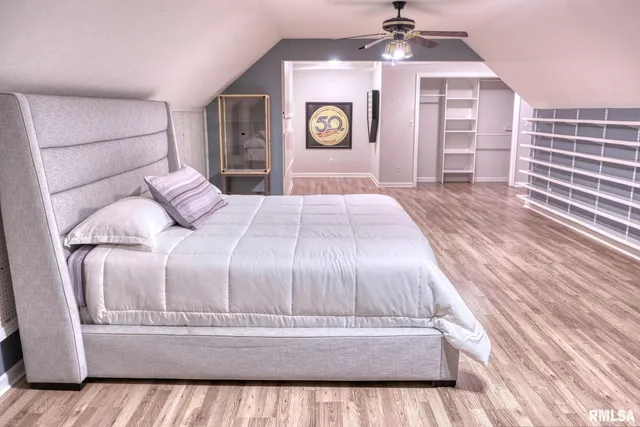 a spacious bedroom with a bed and dresser with wooden floor