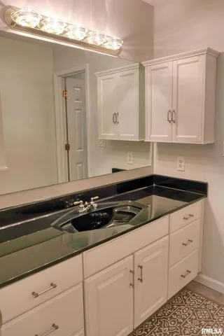 a kitchen with white cabinets and sink