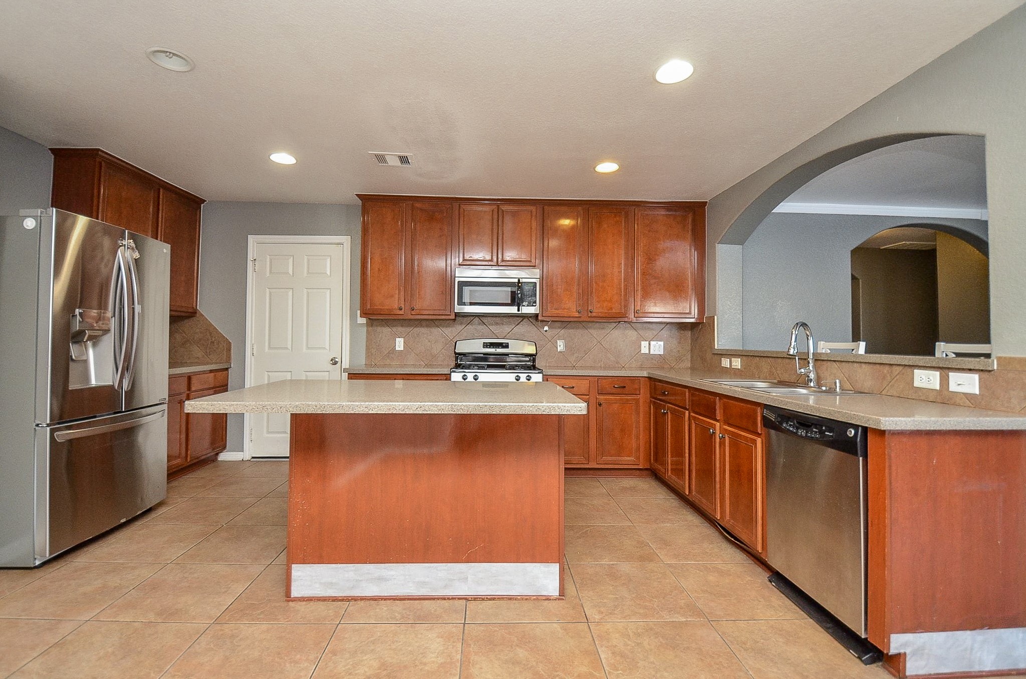 5411 Rio Drive Baytown, TX 77521 - Photo 3 of 30 Bright and spacious kitchen featuring warm wood cabinetry, ample counter space, and a functional open layout ideal for both everyday living and entertaining. A large center island provides additional prep space and seating potential, while the surrounding countertops offer plenty of room for cooking and storage.