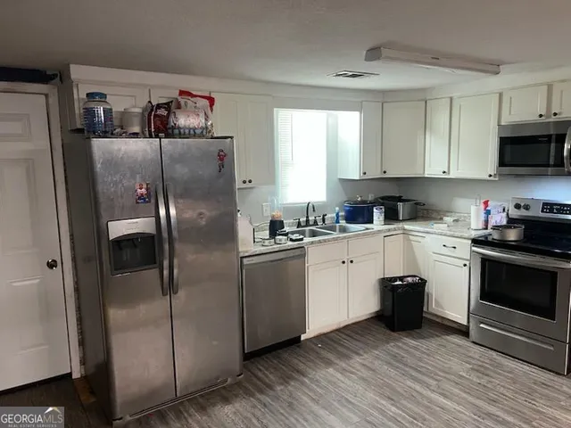 a kitchen with stainless steel appliances a refrigerator sink and white cabinets