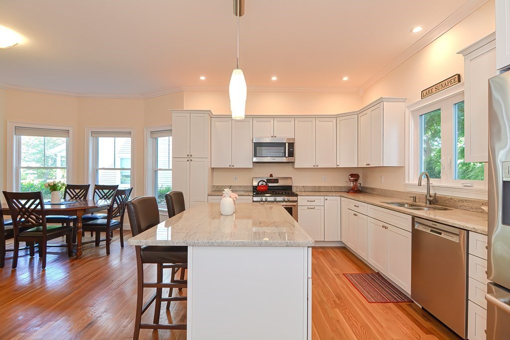 a kitchen with stainless steel appliances granite countertop a stove top oven a sink a dining table and chairs with wooden floor