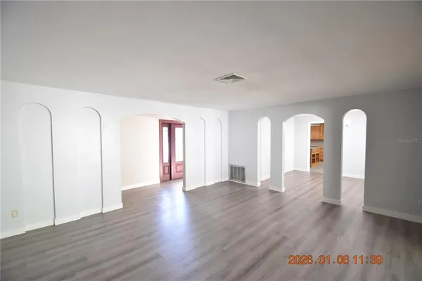 a view of an empty room with wooden floor and window