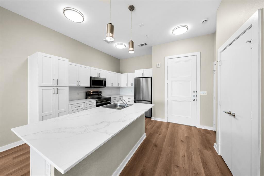 3522 Main Street, Unit 303 Rowlett, TX 75088 - Photo 3 of 23 Kitchen with white cabinetry, decorative light fixtures, appliances with stainless steel finishes, and dark wood finished floors
