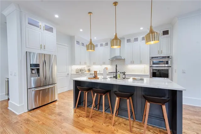 a kitchen with stainless steel appliances granite countertop a sink a stove a refrigerator and island with wooden floor