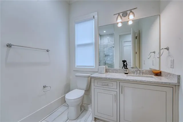 a bathroom with a granite countertop toilet sink and mirror