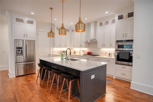 a kitchen with stainless steel appliances kitchen island granite countertop a table chairs stove and refrigerator