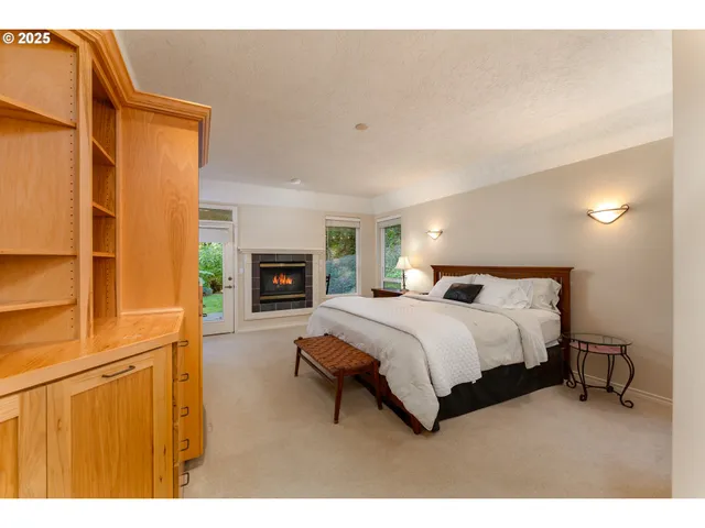a spacious bedroom with a bed lamp on table and a window