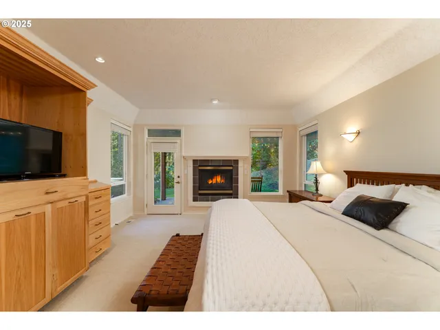 a bedroom with a large bed a flat tv screen and a fireplace